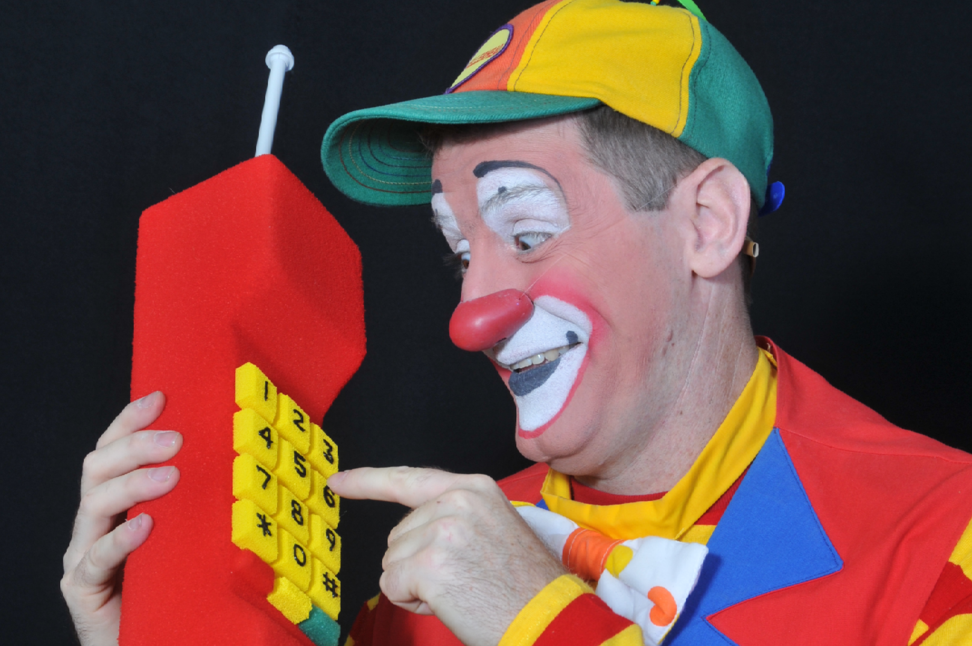 Happy clown dialing large phone